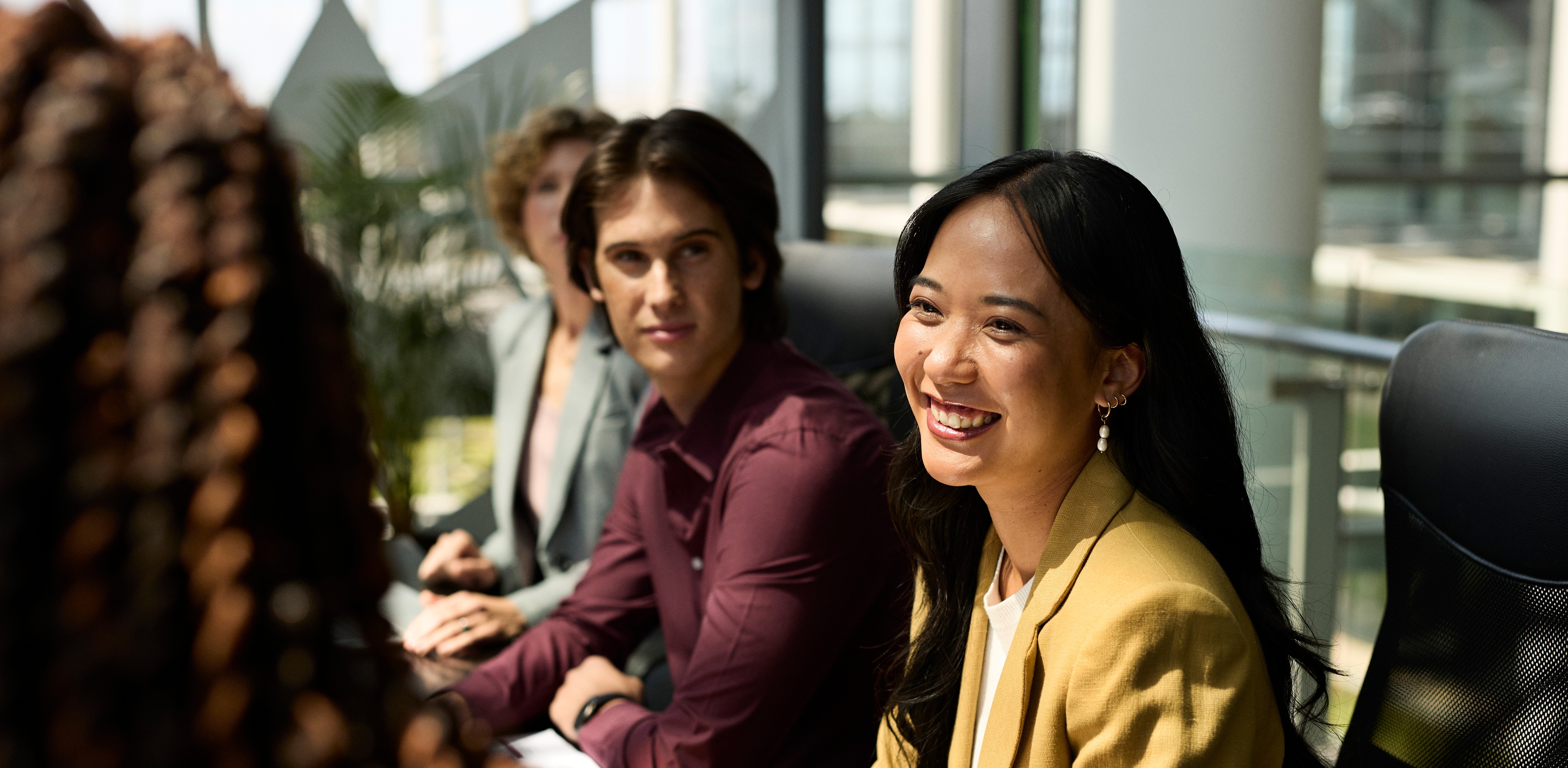 Collaborateurs souriants au travail dans un bureau lumineux, illustrant le bien-être et la prévention en entreprise dans le cadre de la complémentaire santé.
